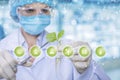 A laboratorian is keeping a sprout in a lab tube and obtaining samples with medical clamp at symbols foreground