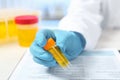 Laboratory assistant holding container with urine sample for analysis at table Royalty Free Stock Photo