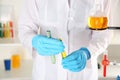 Laboratory assistant holding test tubes with colorful liquids, closeup