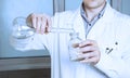 Laboratory assistant pours liquid from a flask.