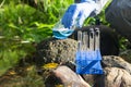 laboratory assistantÃ¢â¬â¢s hand in a rubber glove pours a blue reagent from a flask into a test tube with water to analyze the Royalty Free Stock Photo