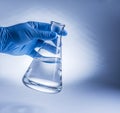 Laboratory beaker in analyst`s hand in plastic glove