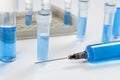 Laboratory bench with vials of blue fluid and a syringe