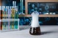 Laboratory flask and test tubes with colorful liquids on white wooden table. Chemical reaction Royalty Free Stock Photo