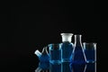 Laboratory glassware with blue liquids on background. Space for text