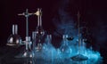 Laboratory glassware, chemical scales, tripod and a torch on dark background in the smoke