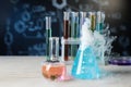 Laboratory glassware with colorful liquids and steam on white table against black background. Chemical reaction Royalty Free Stock Photo