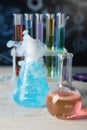 Laboratory glassware with colorful liquids and steam on white wooden table against black background, closeup. Chemical reaction Royalty Free Stock Photo
