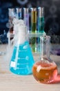 Laboratory glassware with colorful liquids and steam on white table against black background, closeup. Chemical reaction Royalty Free Stock Photo