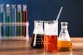 Laboratory glassware with colorful liquids on wooden table, space for text. Chemical reaction Royalty Free Stock Photo