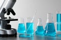 Different laboratory glassware with light blue liquid and microscope on table Royalty Free Stock Photo