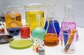 Laboratory glassware with liquids of different colors on white table. Volumetric laboratory glassware over white background Royalty Free Stock Photo