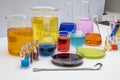 Laboratory glassware with liquids of different colors on white table. Volumetric laboratory glassware over white background