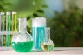 Laboratory glassware and test tubes with colorful liquids on white table outdoors, space for text. Chemical reaction Royalty Free Stock Photo