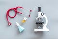 Medical tests on work table of doctor with microscope, stethoscope, test tube, pills on gray background top view