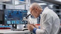 Laboratory with old male scientist observing specimen under microscope Royalty Free Stock Photo