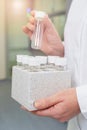 Laboratory scientist holds a plastic box with glass sample tubes.