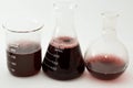 A laboratory set of glassware of conical, boiling and volumetric flasks that contains dark red liquid fluid with bubbles after a Royalty Free Stock Photo