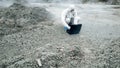 A laboratory technician in a mask and a chemical protective suit opens a toolbox on dry land, around toxic smoke