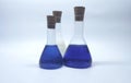 three laboratory conical flasks with blue and white liquid and wooden corks Royalty Free Stock Photo