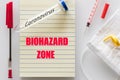 Laboratory vial with the inscription `Coronovirus` Notebook with the red inscription `Biohazard Zone` Concept, epidemiological thr