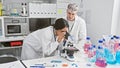 In a laboratory, a woman and man, both scientists, collaboratively work with a microscope and research equipment Royalty Free Stock Photo