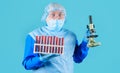 Laboratory work. Doctor in medical mask, protective suit and glasses with test tubes and microscope. Royalty Free Stock Photo