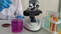 Laboratory worker carries out experiment with microscope and colorful test tubes in the lab concept Royalty Free Stock Photo
