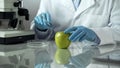 Laboratory worker carrying out research on apple, checking chemical reaction