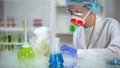 Laboratory worker checking reaction of smoking flasks with colored liquids