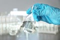 Laboratory worker holding flask with water on blurred background Royalty Free Stock Photo