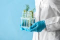 Laboratory worker holding test tubes with plants on color background, closeup Royalty Free Stock Photo
