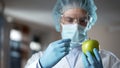 Laboratory worker injecting apple with chemicals, adding smell and juiciness