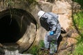 Laboratory worker in a protective suit came to the sewage to take dirty water samples Royalty Free Stock Photo