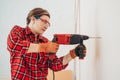 Laborer girl drilling concrete wall with drill