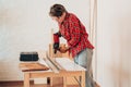 Laborer girl drilling plank with drill on the table