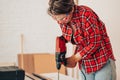 Laborer girl drilling plank with drill on the table