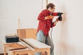 Laborer girl drilling wall with drill