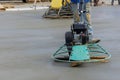 Laborer performing polishing cement screed foundation on the construction site for new house