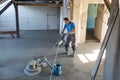 Laborer polishing sand and cement screed floor.
