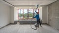 Laborer performing and polishing sand and cement screed wall