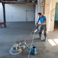 Laborer polishing sand and cement screed floor.