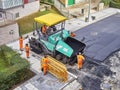 Laborers leveling asphalt during the works for the pavement rehab of a road.