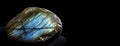 Labradorite is a rare precious natural stone on a black background. AI generated. Header banner mockup with space. Royalty Free Stock Photo