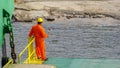 Labuan,Malaysia-July 29,2019:Crew worker in orange coveralls & wearing protective equipment helmet standing on edge of deck while