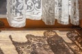 Lace curtains in an old house - bottom of curtains hanging on French door with their shadow cast on old wooden floor