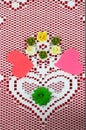 Lace doily with heart on red background with cutout hearts and craft flowers forming a Valenine design