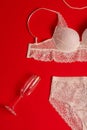 Lace white bra and panties, wine glass and string of pearls on a red background Royalty Free Stock Photo