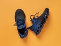 Laced up black blue mesh fabric sneakers over orange background. Pair of grooved men shoes for fitness and active lifestyle. New