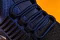 Laced up fastening of new sport shoe against orange background. Lacing of black blue mesh fabric sneakers macro. Modern textile Royalty Free Stock Photo